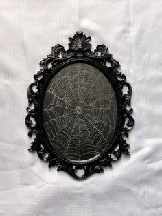 a spider web sits in the middle of a black frame on a white sheeted surface