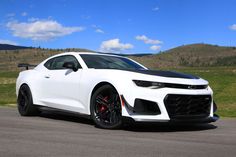 a white chevrolet camaro is parked on the road