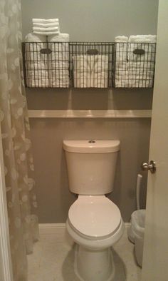 a white toilet sitting in a bathroom next to two baskets on top of the wall