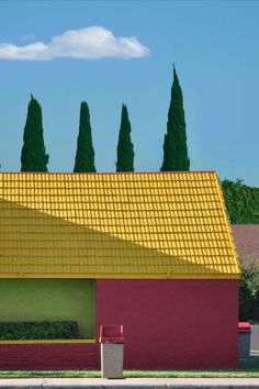 a red and yellow building with trees in the background