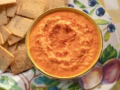 a bowl of dip next to crackers on a plate