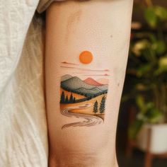 a woman with a tattoo on her arm that has mountains and trees in the background