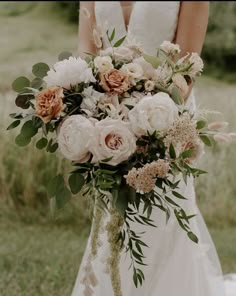 a bridal holding a bouquet of flowers in her hands and wearing a wedding dress