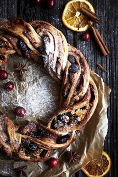 an orange and cranberry cinnamon roll wreath on top of wax paper next to sliced oranges