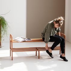 a woman is sitting on a bench with her legs crossed and looking down at the ground