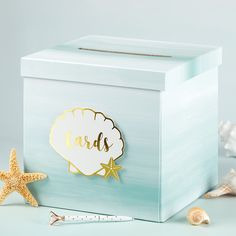 a blue box with a gold name and starfish on the lid next to it