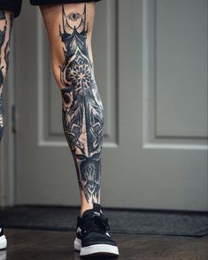 a man with tattoos on his legs and leggings standing in front of a door