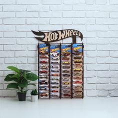 a white brick wall with a sign that says hot wheels on it next to a potted plant