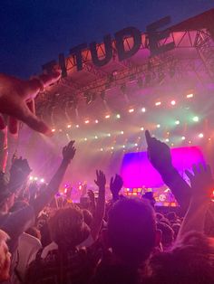 a crowd at a concert with their hands in the air