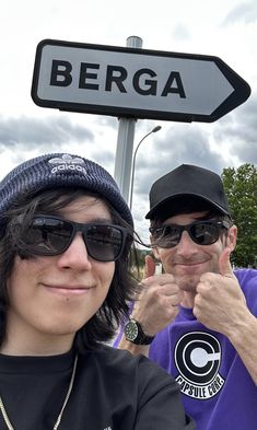 two people standing next to each other in front of a sign that says berga