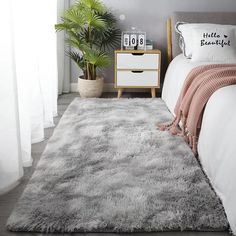 a white bed sitting next to a green plant in a bedroom on top of a wooden floor