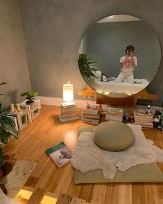 a woman taking a selfie in front of a mirror on the floor with books and candles