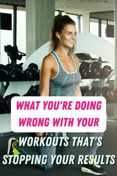 a woman with headphones on standing in front of a rack of dumbbells