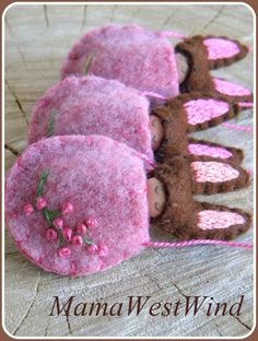 three pink felt dolls are sitting on a wooden surface with the words mama west wind written below them