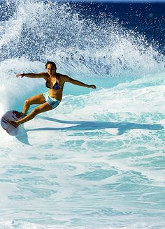 a woman riding a wave on top of a white surfboard in the blue ocean