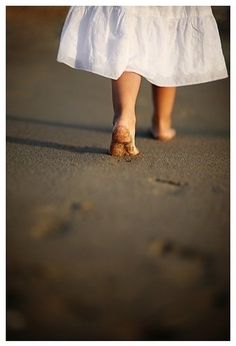 a woman walking down the street with her feet in the sand