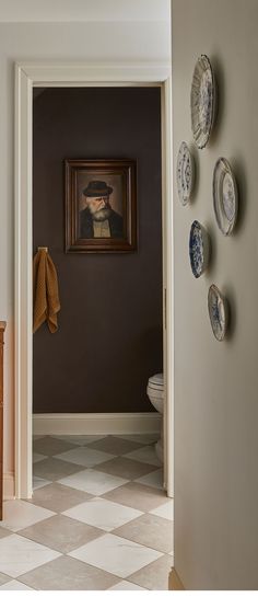 a hallway leading to a bathroom with plates on the wall and a painting above it