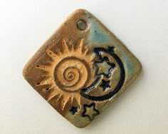 a ceramic tile with a sun and a moon on the bottom, sitting on a white surface