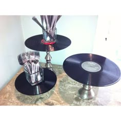 two black and silver records are stacked on top of each other with vases in the middle