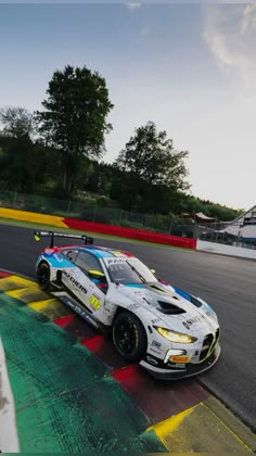 a race car driving on a track with trees in the background