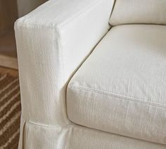 a close up of a white couch in a room with a rug on the floor