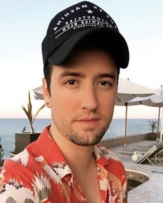 a man wearing a hat standing next to the ocean