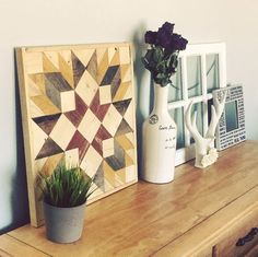 two vases with flowers are sitting on a dresser next to a wooden wall hanging