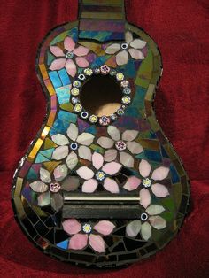 a guitar shaped mirror sitting on top of a red cloth