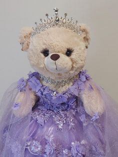 a teddy bear wearing a purple dress and tiara