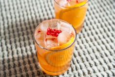 two glasses filled with orange juice and garnished with pomegranates