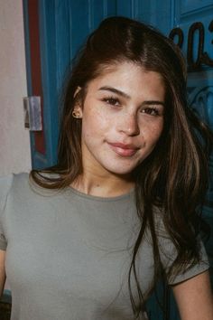 a woman standing in front of a blue door with her hand on her hip and looking at the camera