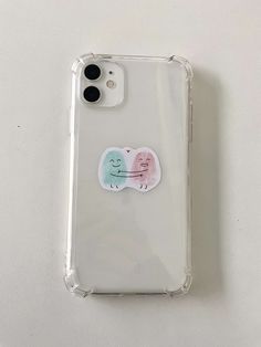 an iphone case with two stickers on the front and back of it, sitting on top of a white surface