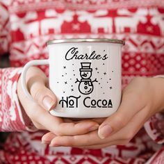 a woman holding a white coffee cup with a snowman on it and charlie's hot cocoa