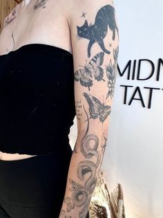 a woman with tattoos standing in front of a wall