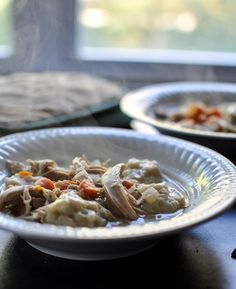 two white plates filled with food sitting on top of a table next to a window