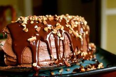 a cake with chocolate frosting and nuts on top is sitting on a black plate