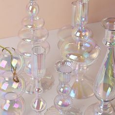 several clear glass vases are sitting on a white table top, one is filled with liquid and the other has a pair of gold eyeglasses