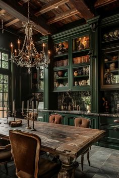 the dining room table is surrounded by green cabinetry and chandelier, along with leather chairs