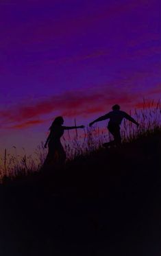 two people walking up a hill at sunset