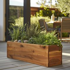 a wooden planter filled with lots of plants on top of a wooden patio floor