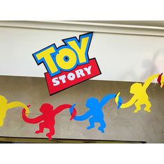 a toy story sign hanging from the side of a building with children's silhouettes painted on it