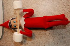 an elf is laying on the floor with marshmallows in front of him