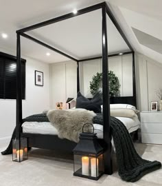 a bedroom with a four poster bed and candles on the floor in front of it