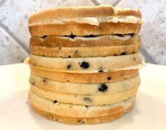 a stack of blueberry pancakes sitting on top of a white plate next to a tiled wall