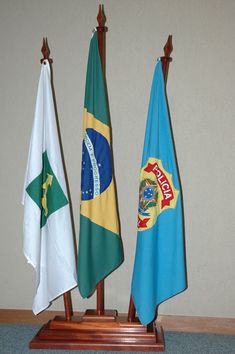 three flags are placed on wooden poles in front of a wall and carpeted floor