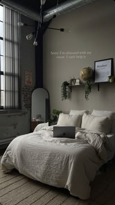 a laptop computer sitting on top of a white bed in a room with high ceilings