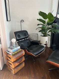 a living room with black leather chairs and a plant