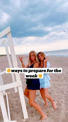 two beautiful young women standing on top of a beach next to a lifeguard chair