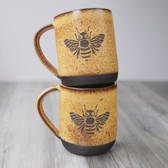 two yellow and black coffee mugs sitting side by side on a wooden table top