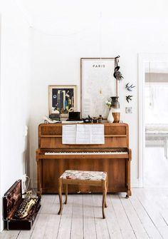 an old piano in the corner of a living room with white walls and wood floors